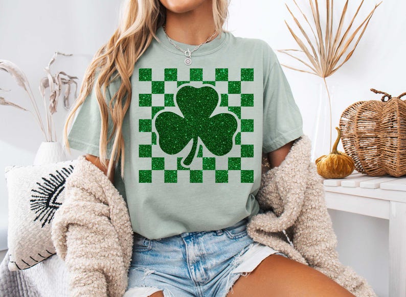 May include: A light green t-shirt with a green glitter shamrock on a green and white checkered background.