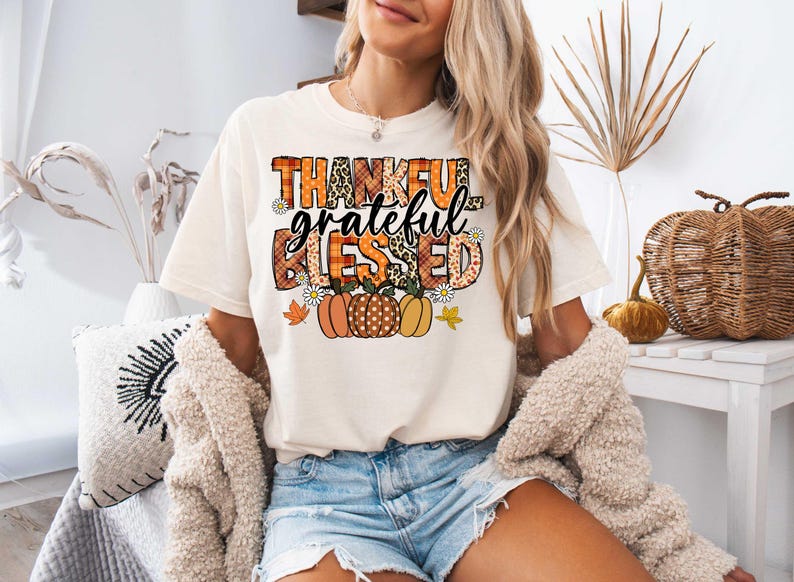 K&ouml;nnte beinhalten: Ein wei&szlig;es T-Shirt mit einem grafischen Design, das "thankful grateful blessed" in einem Patchwork-Stil mit Herbstfarben und K&uuml;rbissen sagt.