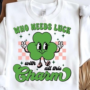 May include: White sweatshirt with a green four-leaf clover cartoon character with the text "Who needs luck with all this charm".