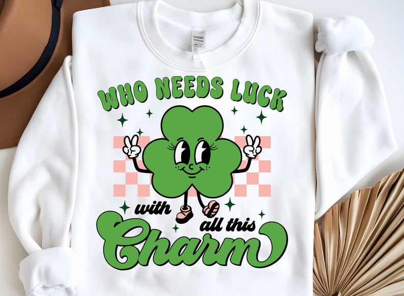 May include: White sweatshirt with a green four-leaf clover cartoon character with the text "Who needs luck with all this charm".