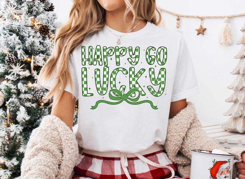 May include: White t-shirt with green and white checkered text that reads "Happy Go Lucky" with a green bow.