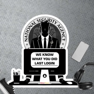 May include: A monochrome sticker design. It features a silhouetted figure in a suit, with the text "NATIONAL SECURITY AGENCY" in a circular design. Below, a computer screen displays "WE KNOW WHAT YOU DID LAST LOGIN."