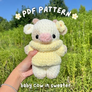 Könnte beinhalten: Ein handgefertigtes Baby-Kuh-Plüschtier in einem gelben Pullover. Die Kuh ist cremefarben mit hellbraunen Ohren und einer rosa Nase. Der Text "PDF PATTERN" und "baby cow in sweater" sind im Bild zu sehen.
