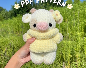 May include: A handmade, plush baby cow in a yellow sweater. The cow is cream-colored with light brown ears and a pink nose. The text "PDF PATTERN" and "baby cow in sweater" are visible in the image.