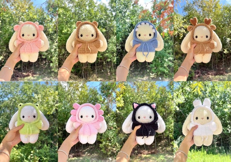 May include: A collection of eight handmade crochet bunny dolls, each wearing a different hooded outfit. The outfits include a pink bear, brown bear, blue shark, brown deer, green frog, pink flower, black cat, and white bunny.