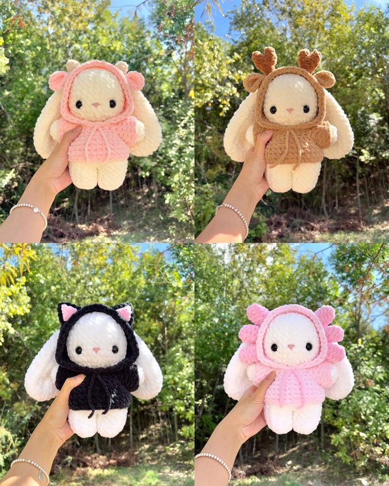 May include: Four handmade crochet bunny dolls, each with a unique hooded outfit. The outfits include a pink deer, brown deer, black cat, and pink flower design. The bunnies are white with black eyes and noses, and the outfits have matching details.