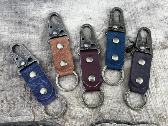 A genuinely handcrafted leather keyfob paired with an antique brass HK-style tactical sling lever snap — the kind of rugged, hardware-forward detail you just don't find in mass-produced accessories.