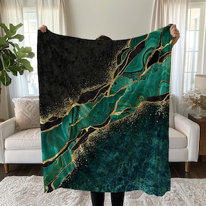 Op de afbeelding: Een zachte, pluche deken met een abstract ontwerp in groen en goud. Het ontwerp heeft draaiende patronen die doen denken aan marmer of agaat.