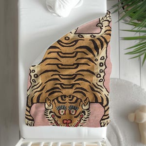 May include: A pink and brown tiger rug with a detailed design. The tiger is lying on its back with its paws in the air. The rug is ideal for a nursery or child's room.
