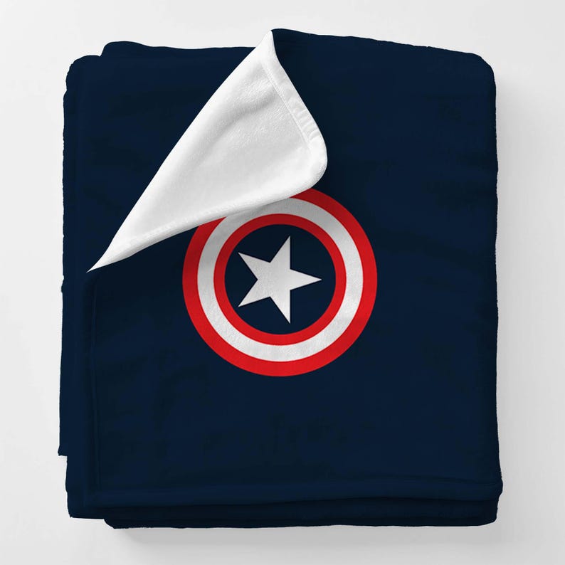 K&ouml;nnte beinhalten: Eine dunkelblaue Fleece-Decke mit einem wei&szlig;en und roten Captain America-Schild-Design. Die Decke hat ein wei&szlig;es Fleece-Futter.