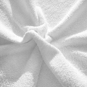 May include: A close-up of a white, fluffy towel with a soft, textured surface. The towel is folded in a way that creates a central point where the fabric meets.