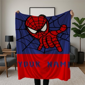Peut inclure: Une couverture bleue et rouge avec un motif Spider-Man. Le design comprend une tête et une main rouges de Spider-Man, un fond bleu avec un motif de toile d'araignée et une section inférieure rouge avec le texte "YOUR NAME".