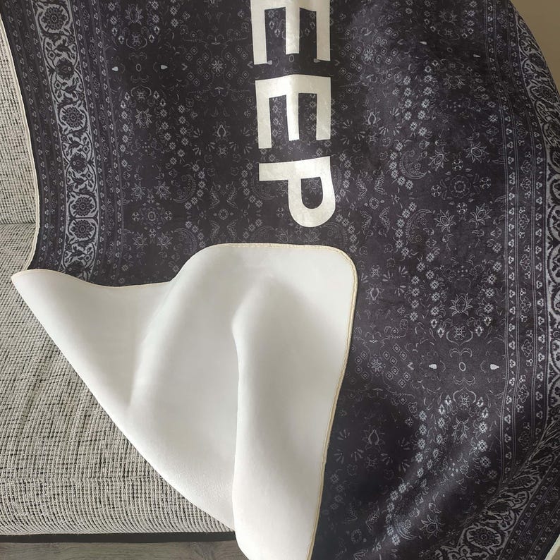 K&ouml;nnte beinhalten: Schwarz-wei&szlig;er Teppich mit Muster und dem Wort "DEEP" in Wei&szlig; auf der Oberseite. Der Teppich hat eine wei&szlig;e R&uuml;ckseite.