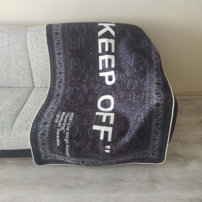 K&ouml;nnte beinhalten: Schwarz-wei&szlig;e gemusterte Decke mit dem Text "KEEP OFF" in wei&szlig;en Buchstaben. Die Decke wurde von IKEA in Zusammenarbeit mit Virgil Abloh hergestellt.