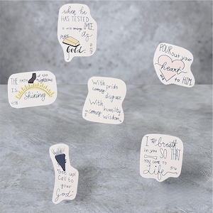 Op de afbeelding: Een verzameling witte stickers met handgeschreven inspirerende citaten en bijbelverzen. De stickers hebben verschillende ontwerpen, waaronder een goudstaaf, een hart en een zon. De tekst bevat zinnen als "Puur Goud" en "Stort je hart uit voor Hem."