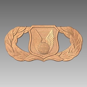 May include: A wooden relief carving of an emblem, featuring a central shield with a globe and wings, flanked by laurel wreaths. The emblem is a light brown color and is set against a gray background. The design is detailed and appears to be a military or organizational insignia.