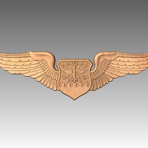 May include: A detailed wooden emblem featuring a central shield with intricate carvings, flanked by outstretched wings. The wings have layered feather details. The emblem is a light brown color and is set against a gray background.