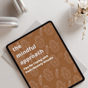 May include: A digital tablet with a brown background and a white pattern of hamsa hands, moons, suns, and feathers. The text "the mindful approach Tips for Coping with Panic/Anxiety Attacks" is displayed on the tablet.