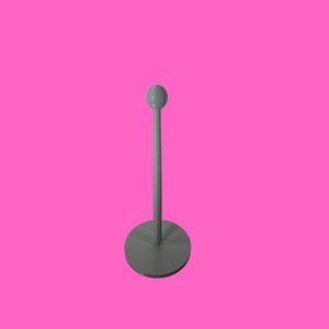May include: A grey metal stanchion with a circular base and a vertical pole, topped with a small sphere. The stanchion is set against a bright pink background.