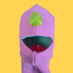 May include: Pink fleece puppet with a green felt nose. The puppet has a large open mouth.