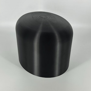 May include: A black, oval-shaped, 3D printed object with a smooth, slightly textured surface.
