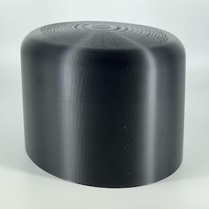 Może przedstawiać: Czarny, gładki, cylindryczny obiekt z lekko zaokrąglonym wierzchołkiem. Obiekt jest wykonany z materiału, który wydaje się być plastikiem lub ceramiką.