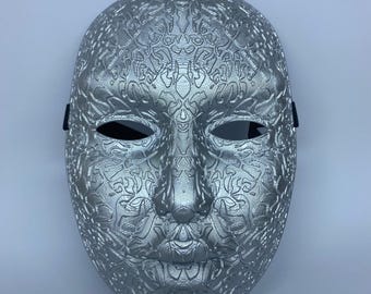 May include: A silver mask with an intricate floral pattern, featuring eye openings and a black strap. The mask has the text "ELF STORE 3D" in gold letters.