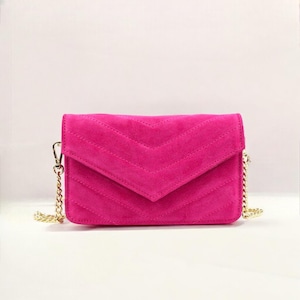Peut inclure: Un sac à bandoulière en daim matelassé rose vif avec une bandoulière chaîne dorée.