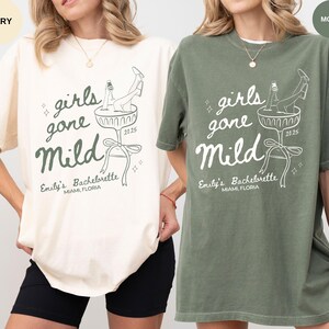 May include: Two oversized t-shirts with a white graphic design of a woman in a champagne glass with the text "girls gone mild" and "Emily's Bachelorette Miami, Florida 2025". The t-shirt on the left is ivory and the t-shirt on the right is moss.