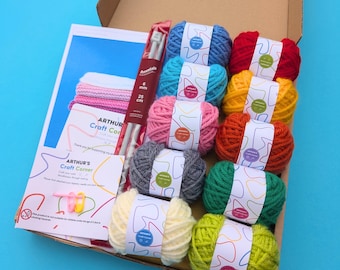 May include: A craft kit in a cardboard box containing ten colourful yarn skeins, a pair of 6 mm by 25 cm knitting needles, two instructional cards labelled Arthur's Craft Corner, and two small plastic stitch markers in pink and yellow.