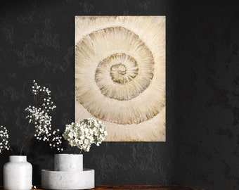 May include: A beige and gold abstract painting with a swirling, concentric circle design. The painting is framed and hanging on a black wall.