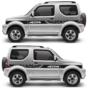 Könnte beinhalten: Ein silberner Suzuki Jimny mit schwarzen und grauen Grafikaufklebern an der Seite. Die Aufkleber zeigen ein 4x4-Logo und ein Rissmuster. Das Auto hat ein schwarzes Dachgepäckträger und schwarze Räder.