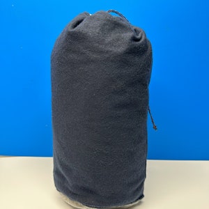 May include: A dark blue drawstring bag made of fabric. The bag is empty and sitting on a white surface.