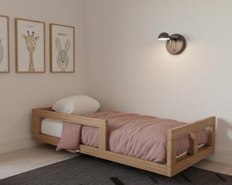 Puede incluir: Un dormitorio infantil con una cama de madera, una colcha rosa y una almohada blanca. Tres estampados de animales enmarcados cuelgan de la pared sobre la cama. Un escritorio y una silla están en primer plano, y una ventana con persianas está a la izquierda.