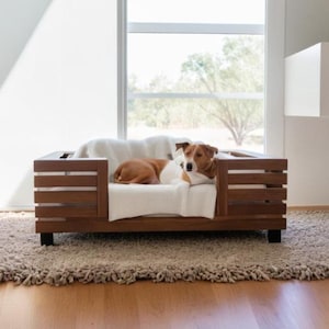 以下が含まれることがあります： スラットデザインの木製犬用ベッド。白いクッションと毛布が特徴です。小さな犬が中で快適に休んでいます。ベッドは、日当たりの良い部屋のシャギーラグの上にあります。