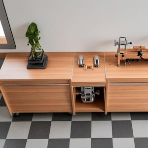 Peut inclure: Un établi en bois avec deux tiroirs et une étagère. L'établi est surmonté d'un tour à bois et d'autres outils. L'établi se trouve dans une pièce avec un sol en damier.