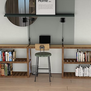 May include: A wooden desk with two open shelves on each side, filled with books. The desk has a light wood top and dark wood frame. A green stool sits in front of the desk. The desk is against a light gray wall with a black shelf above it. The shelf has a framed print with the word "Home" on it.