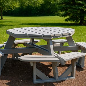 May include: A gray, octagonal picnic table with attached benches. The table has a slatted top and is made of wood. The benches are attached to the table and provide seating for multiple people. The table is outdoors on a grassy area.