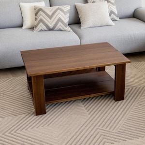 Op de afbeelding: Een donkerbruine houten salontafel met een lager plank. De tafel staat op een beige kleed met een geometrisch patroon.