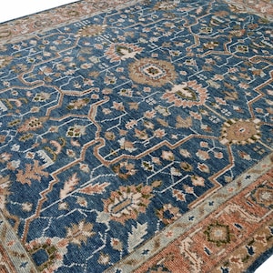 Alfombra de lana estilo Heriz anudada a mano con diseño floral tradicional persa en tonos azules, óxido y oliva.