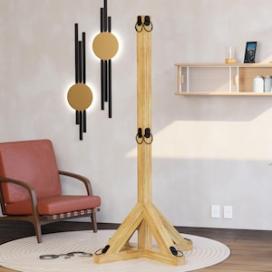 Op de afbeelding: Een houten constructie met een basis en een hoge verticale paal, met metalen ringen. De constructie staat op een rond tapijt, met een rode fauteuil en decoratieve wandkunst op de achtergrond. De tekst onderaan luidt: STEP-BY-STEP PDF PLANS - BUILD IT YOURSELF - INSTANT DOWNLOAD.
