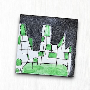 May include: A black and white ceramic tile with a green and black abstract design. The tile has a grid pattern with green squares and black lines. The text "Emma Love 2021" is written in black on the tile.