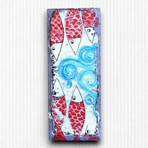 May include: A rectangular ceramic tile with a painted design of five red and white fish swimming in blue water. The fish have scales and are facing the same direction. The water is depicted with blue swirls.