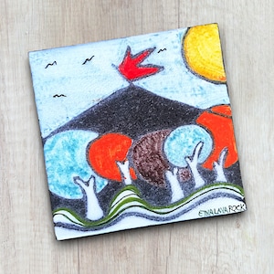 Könnte beinhalten: Eine farbenfrohe Keramikfliese mit einem schwarzen Berg, roten Flammen, orangefarbenen und blauen Bäumen und einer gelben Sonne. Die Fliese ist mit "ETNA LAVA ROCK" signiert.