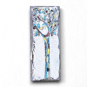 Peut inclure: Un carreau de céramique avec un motif peint d'un arbre stylisé avec des feuilles bleues, jaunes et brunes. Le tronc de l'arbre est peint dans des tons de bleu, jaune et rouge.