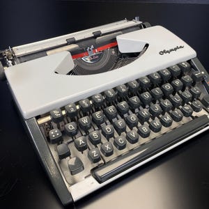 Máquina de escribir Olympia DeLuxe vintage, totalmente funcional, limpia y con mantenimiento, portátil con estuche, color blanco y gris pizarra.