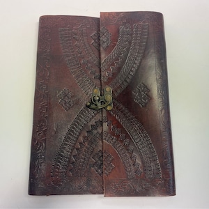 Peut inclure: Un journal en cuir marron avec un motif gaufré décoratif et une fermeture à fermoir en laiton.