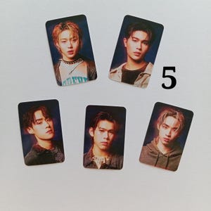 Op de afbeelding: Vijf rechthoekige fotokaarten met portretten van jonge mensen. De kaarten hebben een glanzende afwerking en zijn gerangschikt op een wit oppervlak. Het nummer "5" is in het zwart aan de rechterkant van de kaarten geschreven.