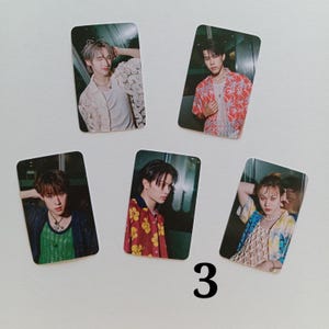 Op de afbeelding: Vijf rechthoekige fotokaarten met jonge mensen in verschillende outfits. De kaarten zijn gerangschikt op een wit oppervlak. De onderwerpen dragen shirts in kleuren als rood, wit en blauw. Het nummer "3" is in zwart op het oppervlak gedrukt.