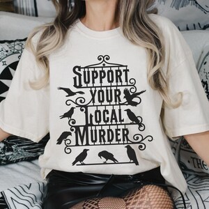 black iron gate with several crows and text Support Your Local Murder